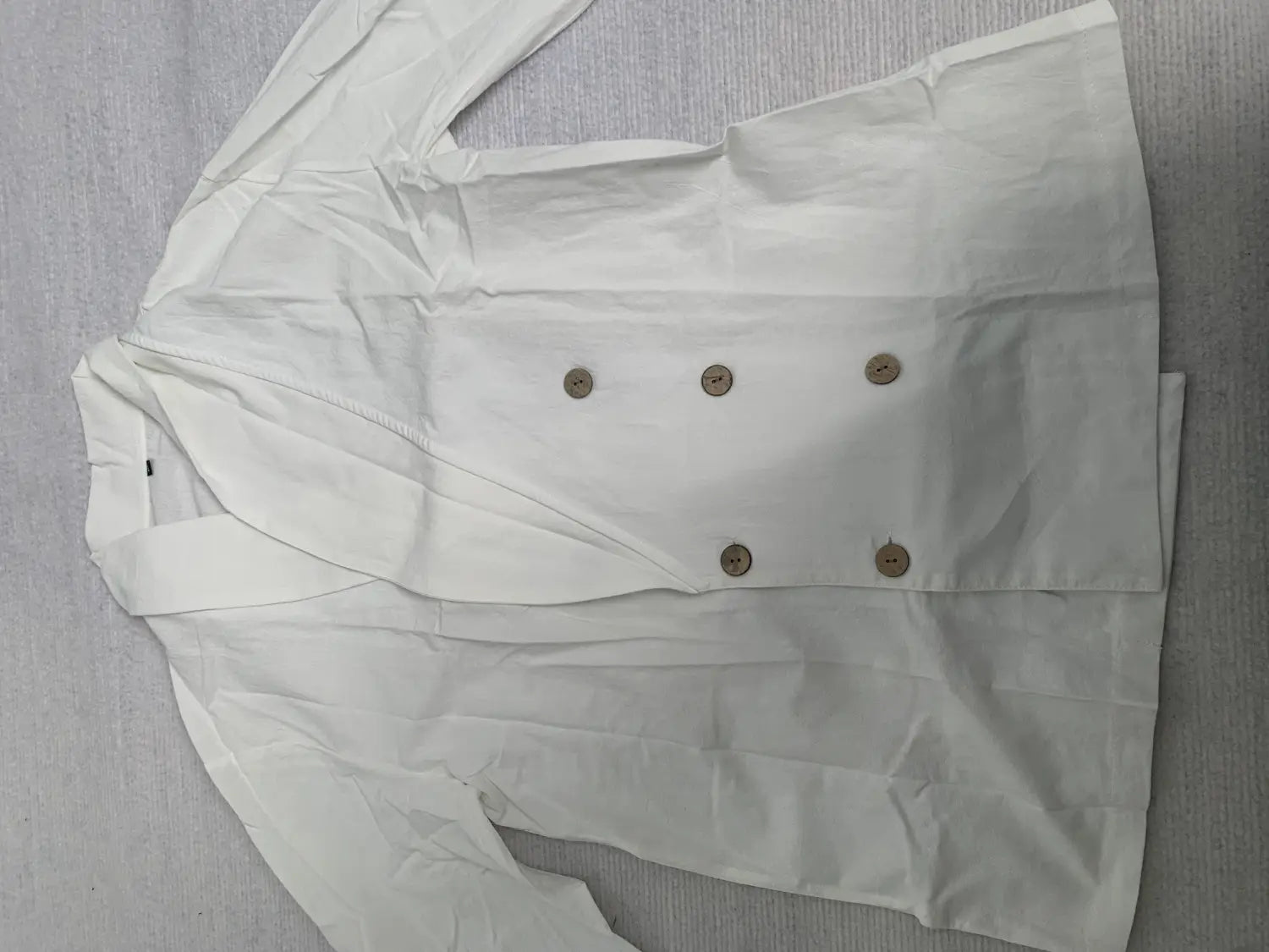 white double-breasted blazer with beige buttons paired with men long sleeve linen mandarin collar casual shirt displayed.