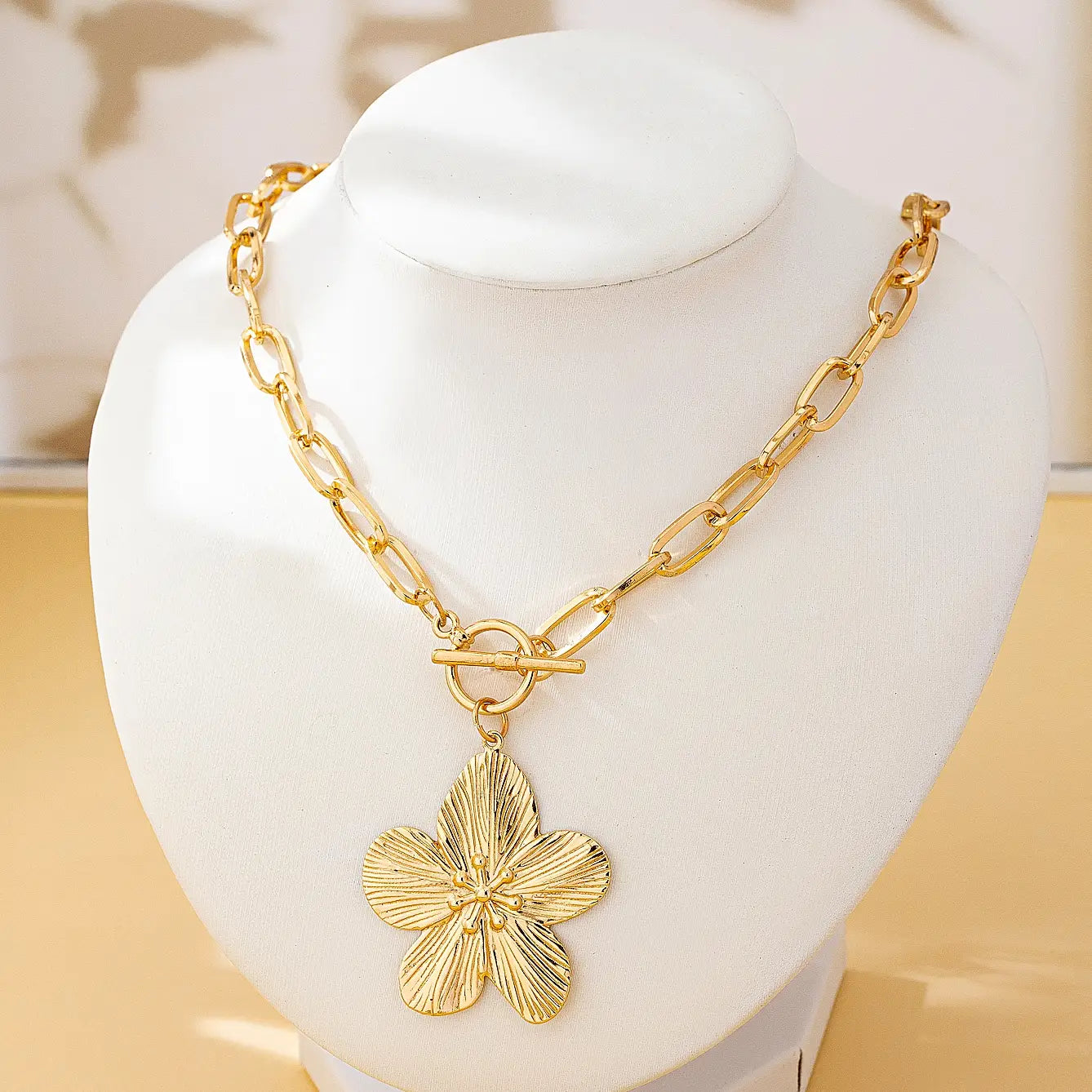 Collier pendentif plaqué or présentant un pendentif de fleur de glycine à cinq pétales texturé et une attache à bascule pour femmes, style vintage.