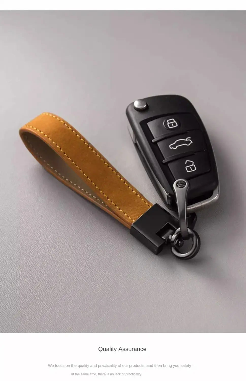 Echter Lederschlüsselanhänger mit minimalistischem Schlüsselring aus Tan-Leder mit schwarzen Kunststoff- und Metallelementen, entworfen, um in eine moderne Autofernbedienung zu passen.