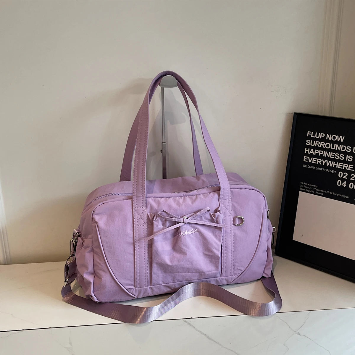 Lavender-colored durable nylon travel duffel bag with large capacity front pocket featuring a bow detail and adjustable shoulder strap for women handbag.