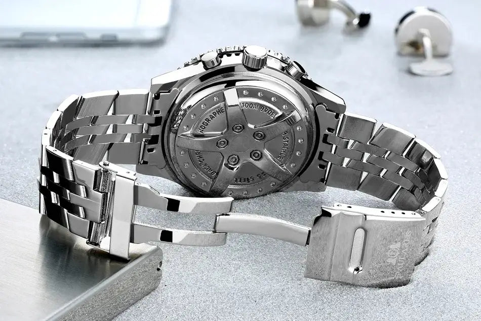 Automatische mechanische Herrenuhr mit blauem Zifferblatt und silberfarbenem Edelstahl-Chronographen, sichtbar vom polierten Gliederarmband mit ineinandergreifenden Elementen und dem runden Gehäuseboden mit eingraviertem Text.