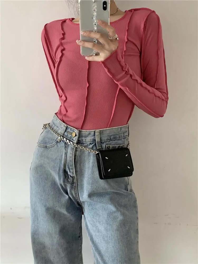 Schwarze rechteckige Umhängetasche mit silbernem Kettenriemen und weißen Ziernähten, kombiniert mit einem hellblauen gerippten Longsleeve-Top für Damen im schlanken Casual-Stil.