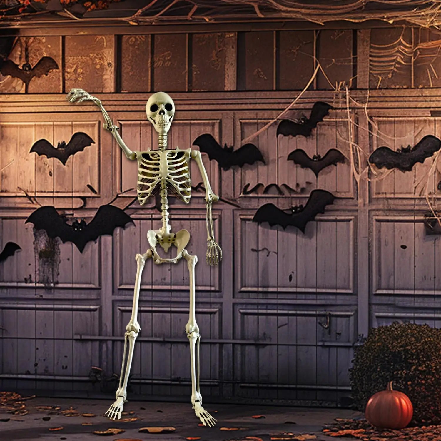 un esqueleto de plástico de Halloween color verde pálido y de gran altura con extremidades articuladas y una caja torácica detallada, colocado como decoración de jardín delante de una puerta de garaje decorada para una casa encantada.