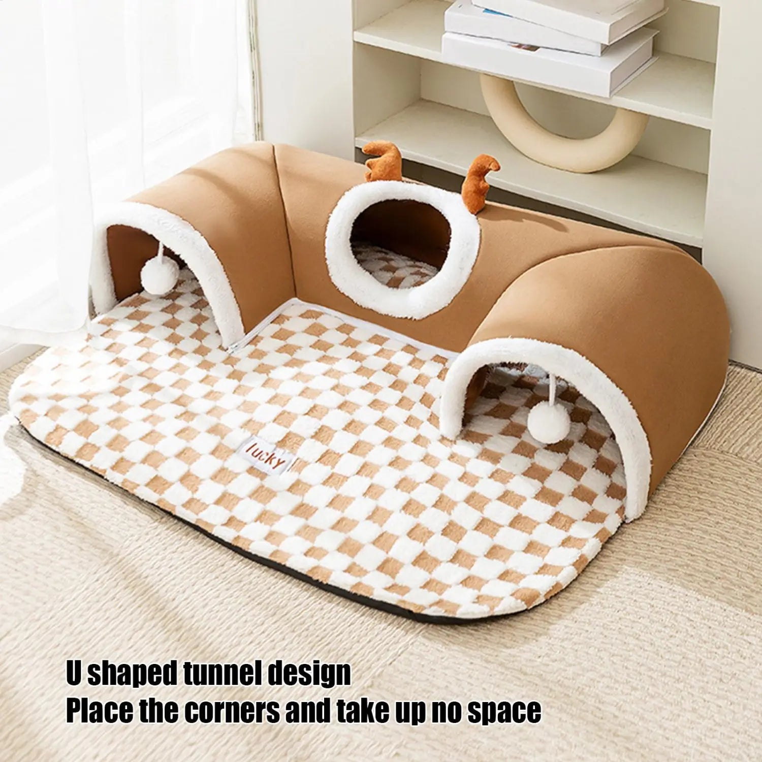 Tan and white u-shaped cat tunnel bed with a checkered pattern, plush fabric, and small decorative antlers for a cozy cat tunnel bed corner hideaway.