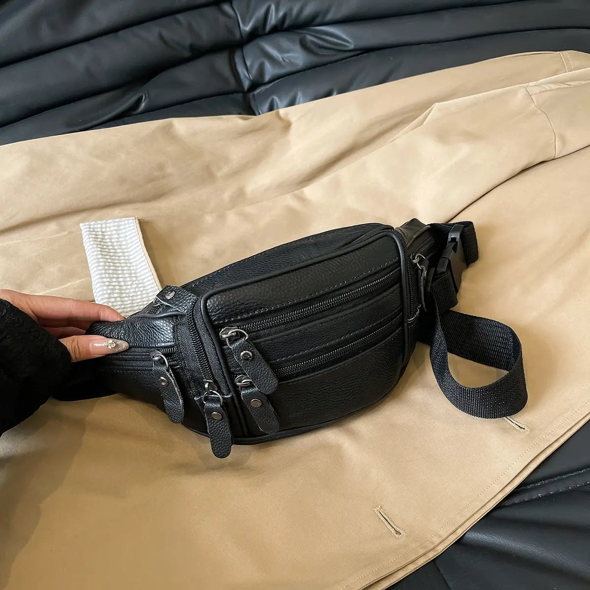 Schwarze Gürteltasche aus echtem Leder mit mehreren Reißverschlussfächern und einem verstellbaren Riemen zur vielseitigen Verwendung als Crossbody- oder Bauchtasche.