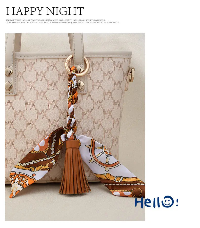 Porte-clés à gland de foulard en soie pour sacs, avec une conception tressée utilisant des fils orange brun et blancs, et un gland évoquant le cuir beige.