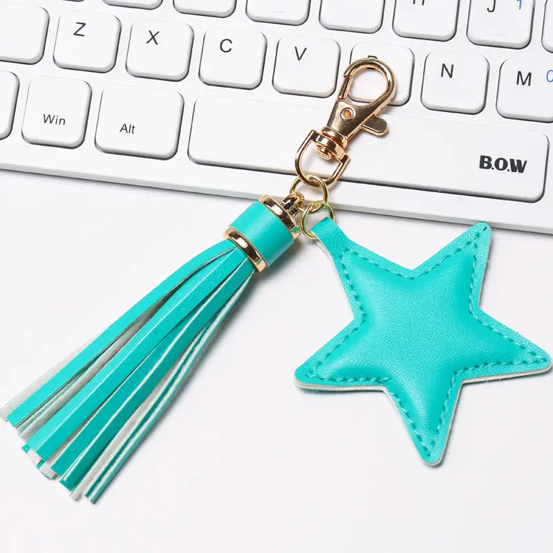 Turquoise star-shaped leather keychain with matching tassel and gold-tone metal clasp for women.