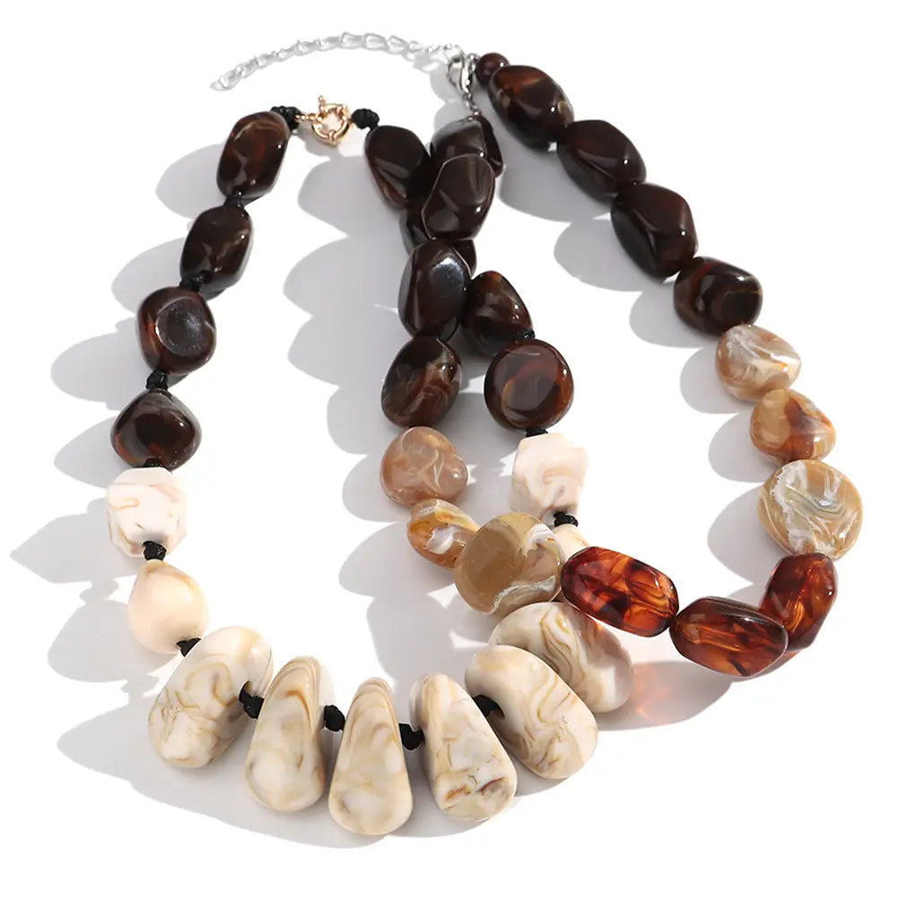 Collier ras du cou en résine à motif géométrique, fait de perles marbrées, présentant une conception superposée avec des perles irrégulières façonnées et polies, de couleur ambre et aux tons crème.