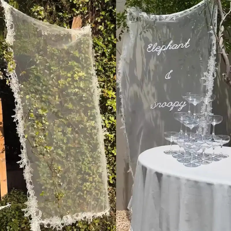 Individuelles Willkommensschild aus Spitze als Banner mit transparentem weißem Spitzestoff, feiner floraler Stickerei und Hintergrund mit gekräuselter Kante.