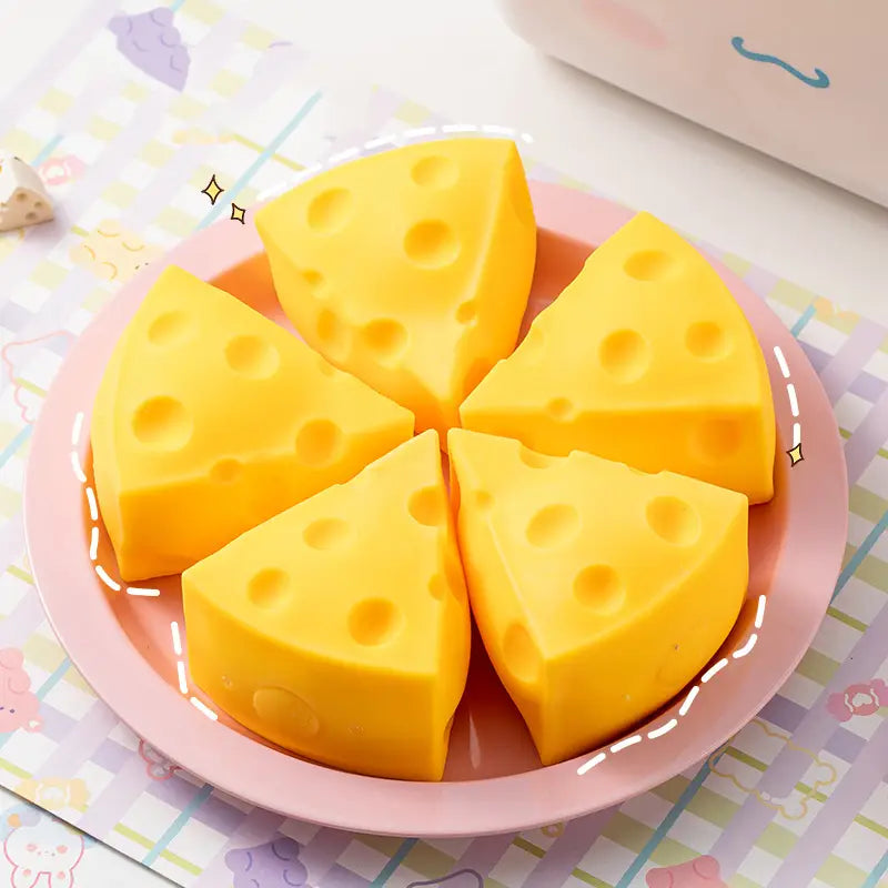 Savons à base de mousse jaune, en forme de fromage, de type jouet antistress qui s’écrase, disposés sur une assiette rose, idéals comme cadeaux pour les fêtes et jouets sensoriels à faire lentement monter.