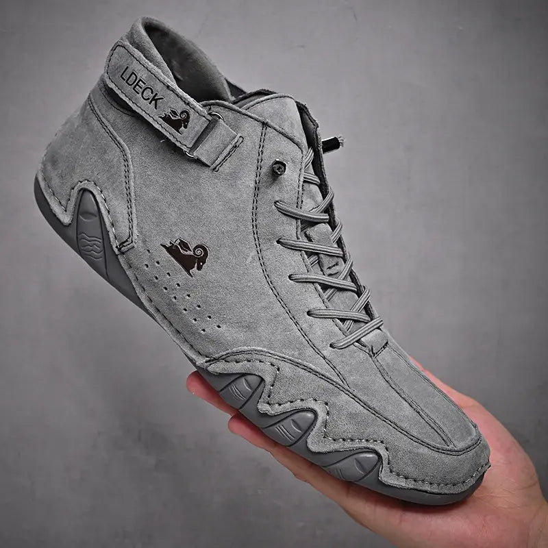 Men high top leather casual sneakers in gray suede with black logo detailing and a textured rubber sole.