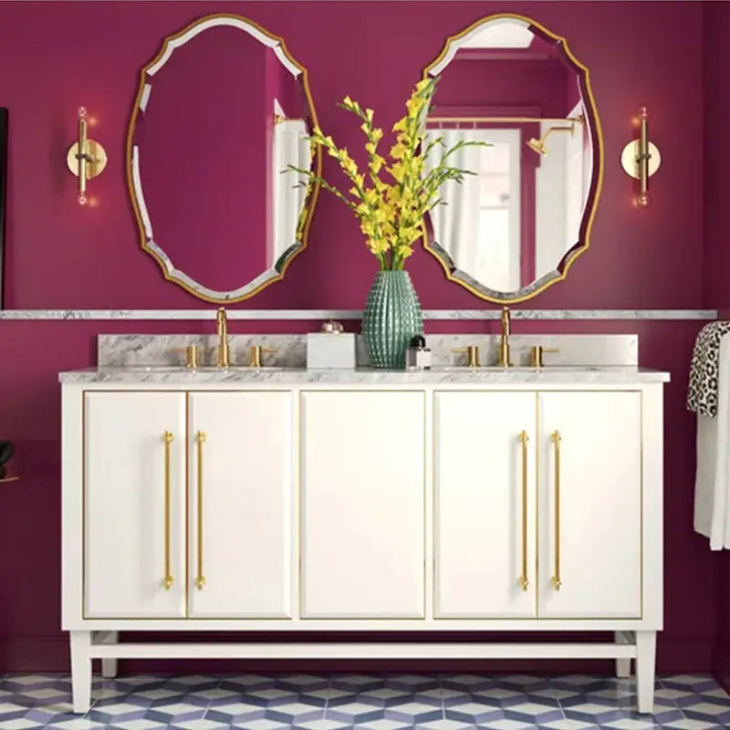 Meuble-lavabo blanc avec quincaillerie dorée et plan de travail en marbre, associé à un miroir de salle de bains ovale doré ornemental pour une décoration murale élégante