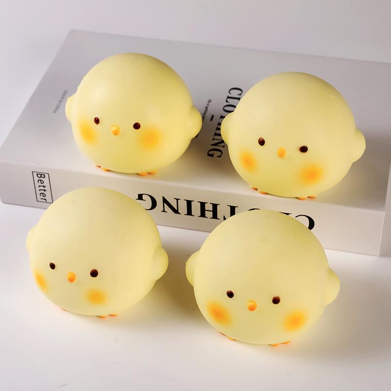 four soft pale yellow chick-shaped stress balls with orange cheeks and tiny feet made of slow rising material designed as a fidget toy for daily stress relief.