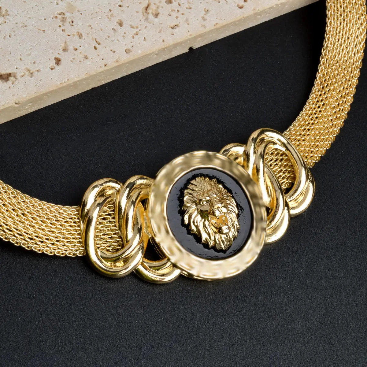 Juego de joyería de león de oro de Dubái de 18 quilates que presenta un collar tipo gargantilla de malla dorada con un medallón circular central negro, en relieve con una cabeza de león dorada.