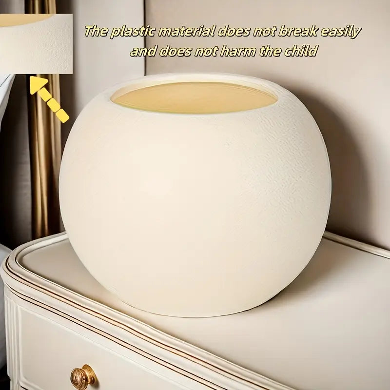 Un pot à fleurs rond en plastique léger de couleur crème, à la finition mate lisse et à un rebord légèrement surélevé, idéal pour la plantation de fleurs à domicile en intérieur et en extérieur.