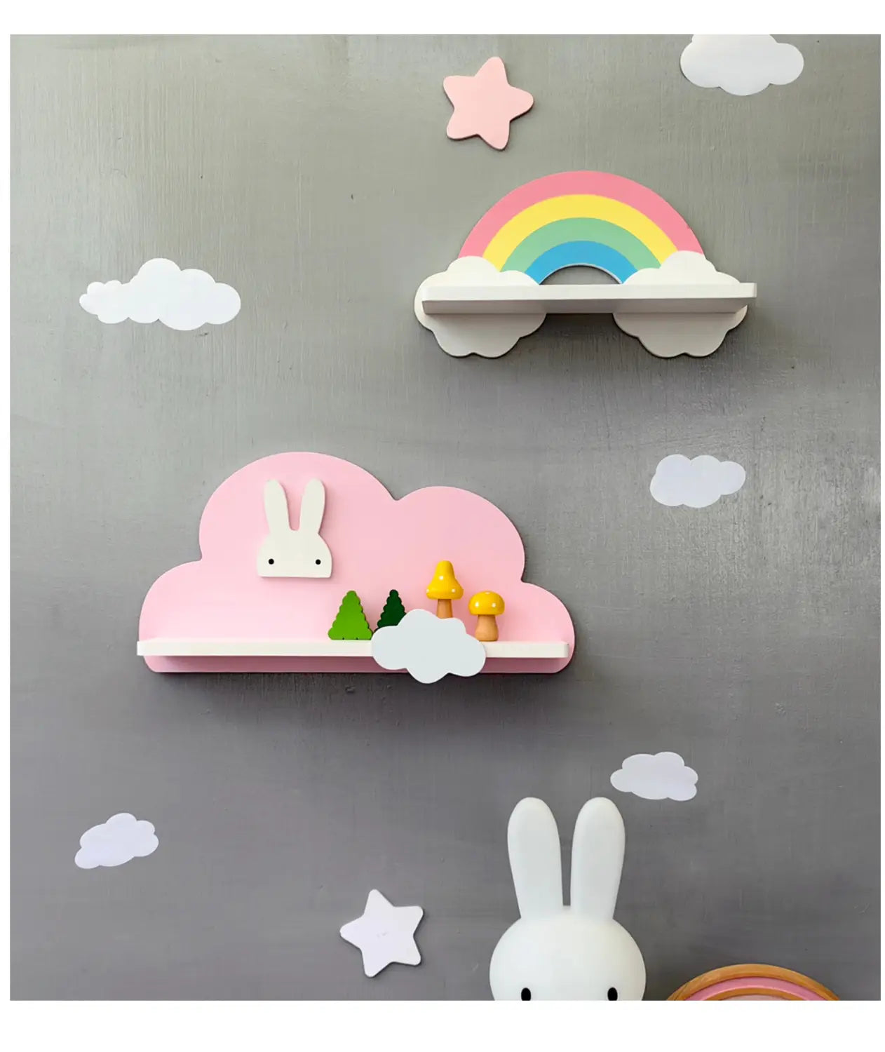 Ein rosa, wolkenförmiges Bücherregal aus Holz für Kinder an der Wand mit einer weißen Hasenfigur, Miniaturbäumen und Pilzen auf der Ablage