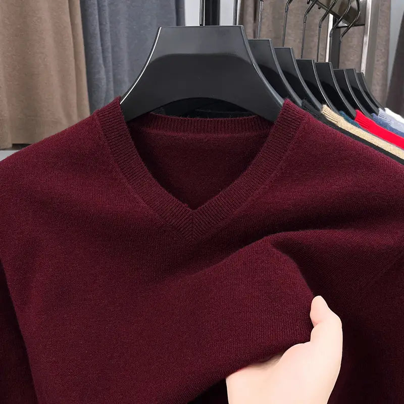 Herren-V-Ausschnitt-Strickpullover in sattem Burgunderrot mit weicher gestrickter Struktur, auf einem schwarzen Kleiderbügel hängend