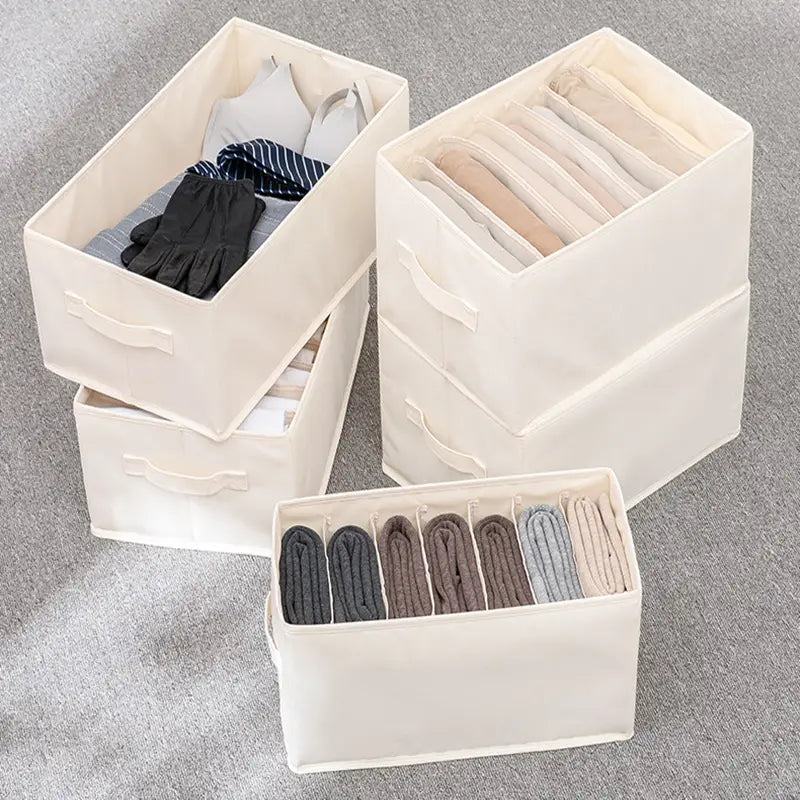 off-weiße Stoff-Wäscheaufbewahrungsbox mit integrierten Griffen und internen Trennwänden, ausgelegt für die Organisation im Kleiderschrank und für Jeans.