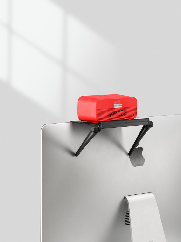 adjustable screen top storage shelf monitor stand with a red rectangular speaker with a matte finish mounted on a black adjustable stand.