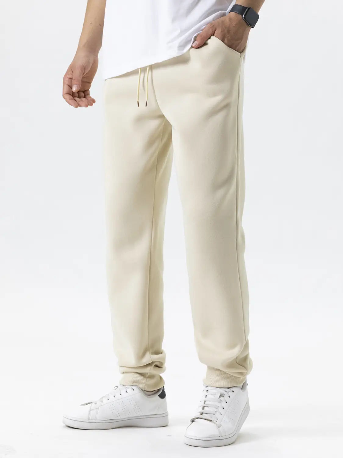 Pantalons de jogging en polaire pour hommes, couleur écrue, en coton, avec une taille à cordon de serrage et des poignets fuselés adaptés à une tenue d’hiver décontractée.
