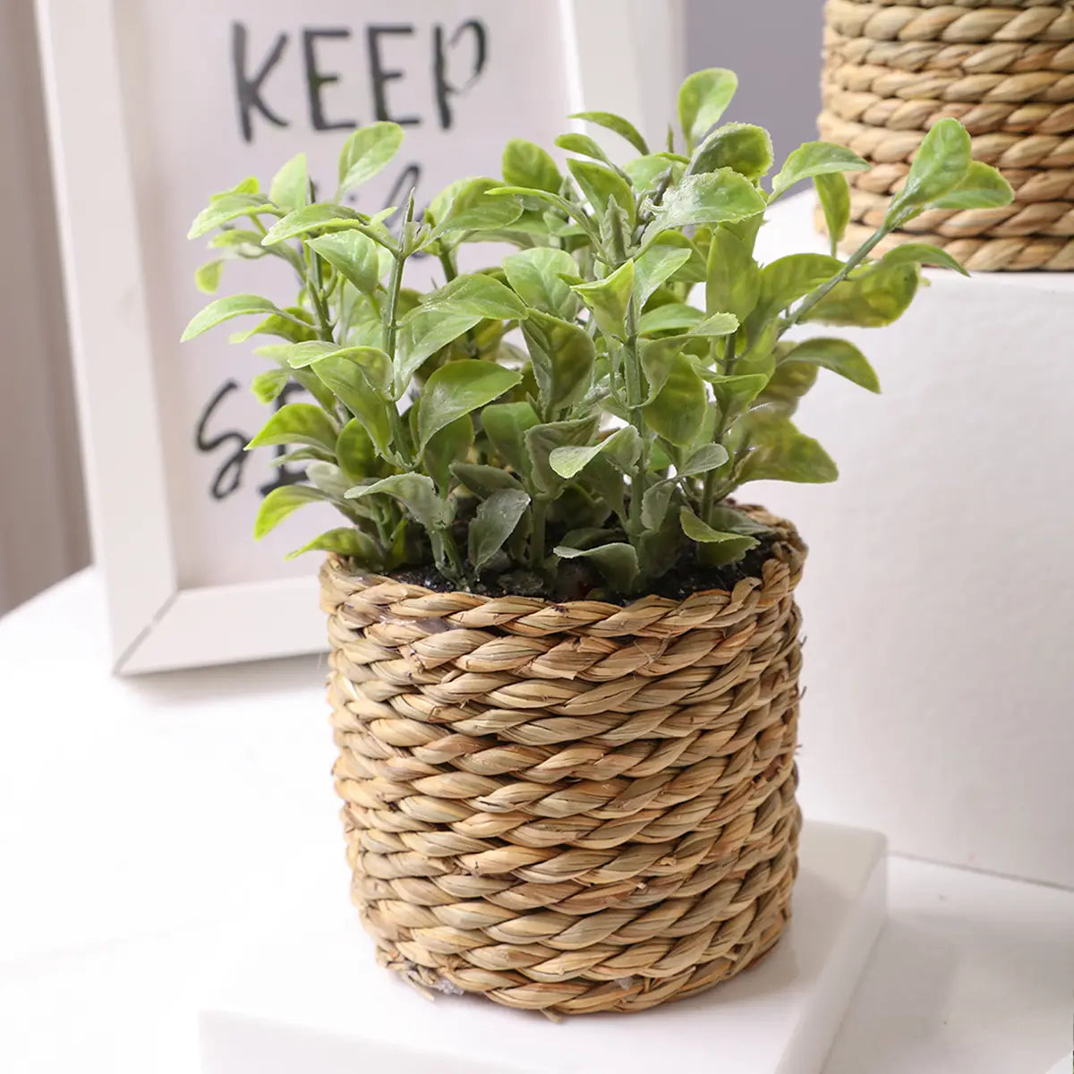 a woven natural fiber pot holding a small potted artificial plant with lush green eucalyptus flowers and detailed leaves measuring 17cm