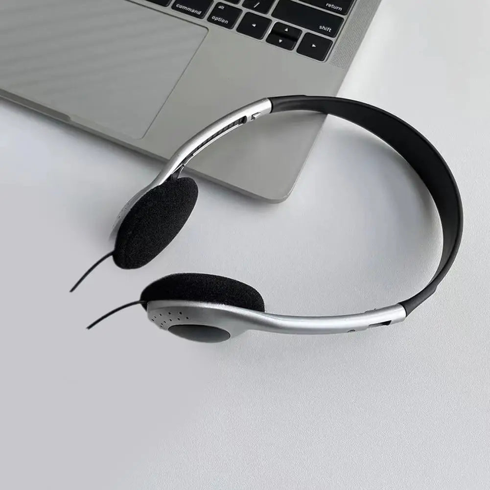 Casque d’écoute supra-auriculaire rétro filaire argent et noir avec coussinets d’oreille rembourrés posés à côté d’un ordinateur portable.