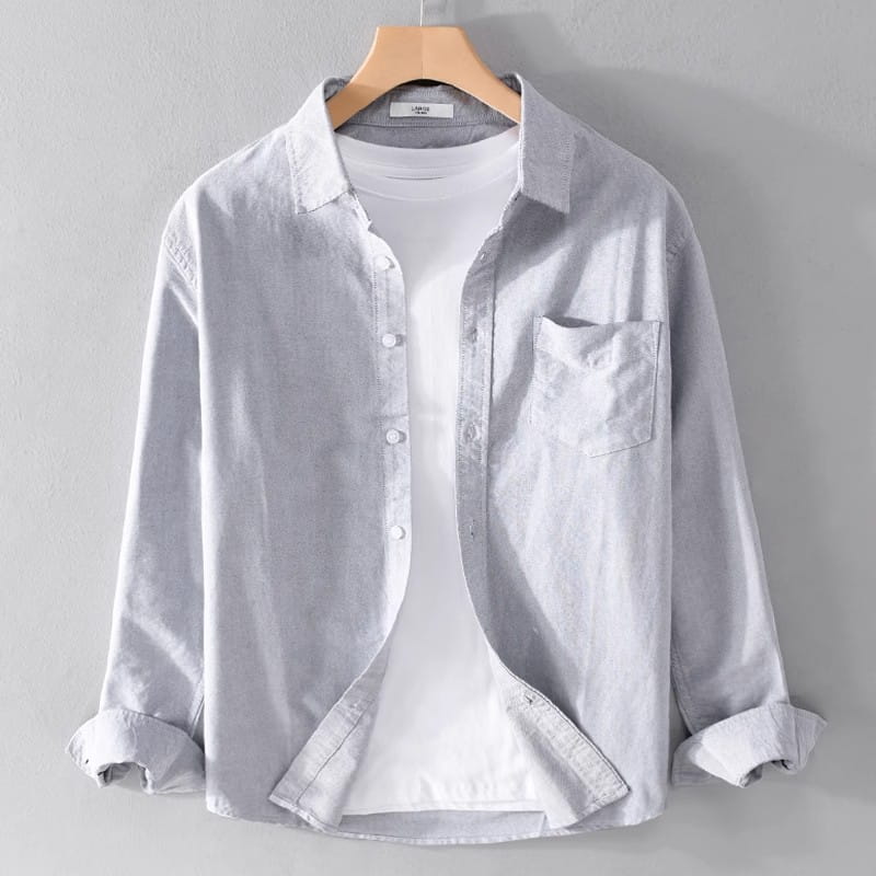 Light gray durable casual long sleeve work shirt made of sturdy material with a chest pocket and rolled cuffs hanging on a wooden hanger.