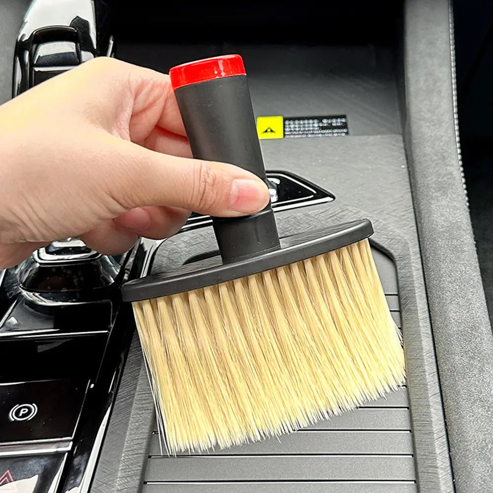 Eine Detailbürste für die Autopflege mit schwarzem und rotem Griff und weichen hellbeigen Borsten, ausgelegt für die Innenraumreinigung.