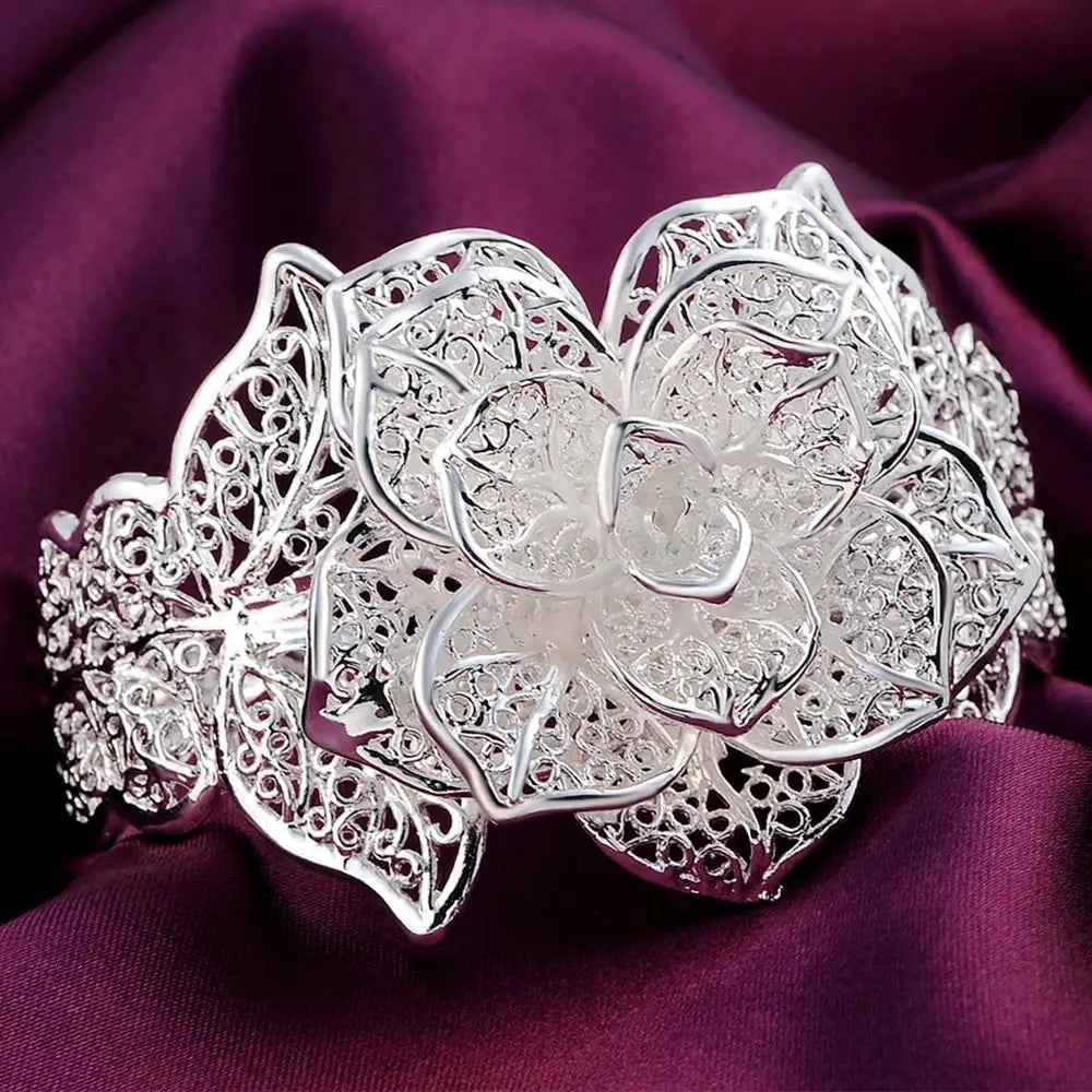 Parure de bijoux floraux en argent sterling comprenant un bracelet manchette de fleur en filigrane d’argent, avec des détails délicats de type dentelle et des pierres scintillantes serties.
