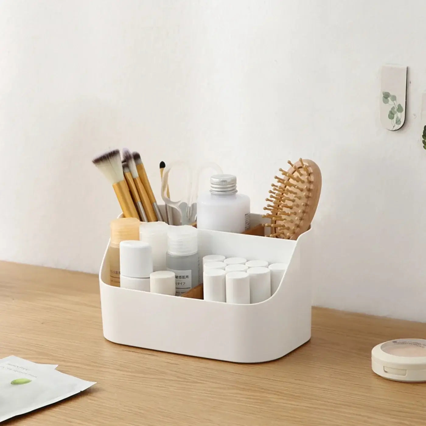 White plastic desk organizer and makeup brush holder with multiple compartments holding brushes bottles and a wooden comb.