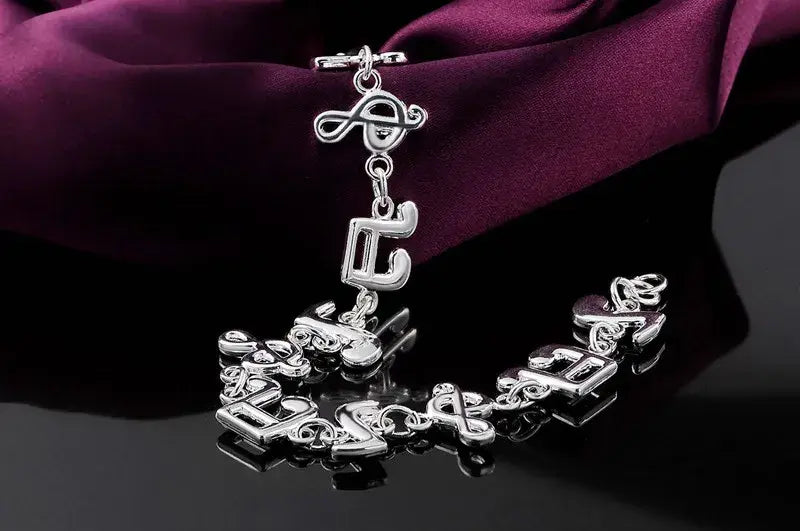 Silver musical note sterling silver bracelet featuring a toggle clasp and dangling charms.
