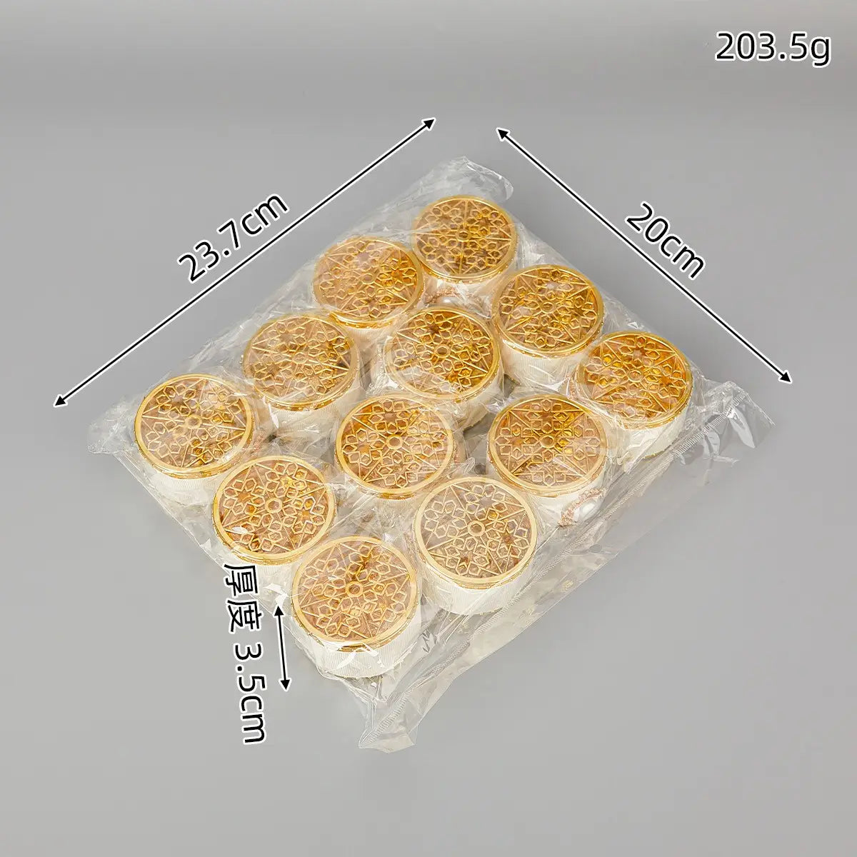 Boîte à bonbons de mariage dorée décorative contenant une perle-bonbon, avec des supports de bougies circulaires dorés finement travaillés, dotés d’une base blanche.