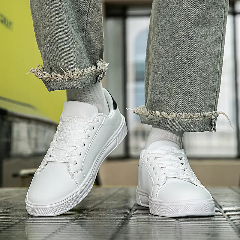 Weiße Ledersneaker im Freizeitstil mit einem klaren minimalistischen Low-Top-Design und dezenten schwarzen Akzenten an der Ferse für sportliche Leichtgewichtsanwendungen.