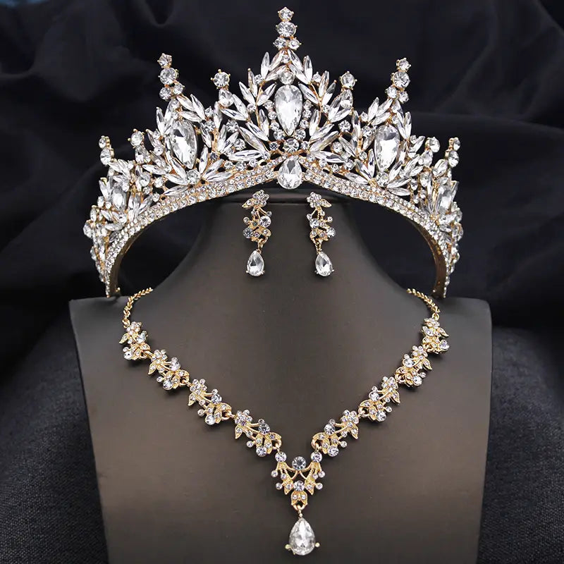 Un ensemble de couronne de mariée et de bijoux étincelant en or éclatant et cristaux transparents, avec des motifs de feuilles complexes et des pierres en forme de goutte pour des accessoires de mariage.