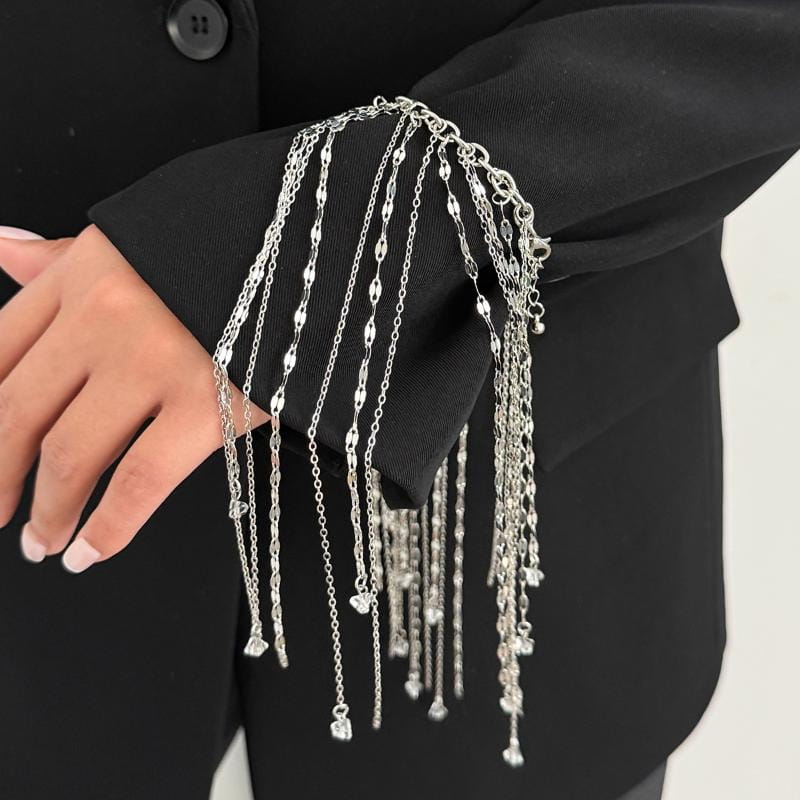 bracelet en chaîne d'argent pour femmes, avec plusieurs brins suspendus, des charmes en forme de cœur et une finition métallique élégante dans un design à gland géométrique.