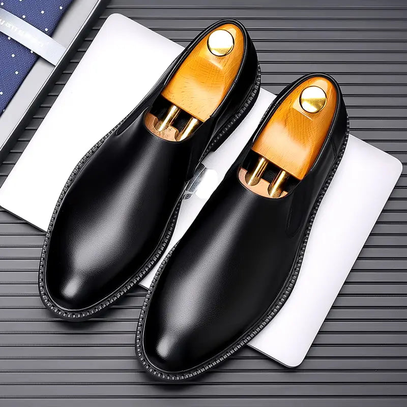 Chaussures habillées à enfiler en cuir pour hommes, noires, avec semelles intérieures en bois à tonalité dorée et détails de couture sur le bord.