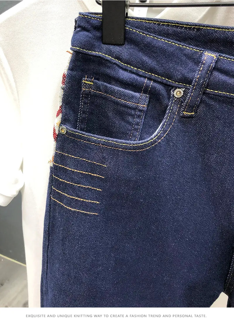 Men slim fit stretch denim jeans in dark blue with yellow stitching and a decorative embroidered patch on the side seam.