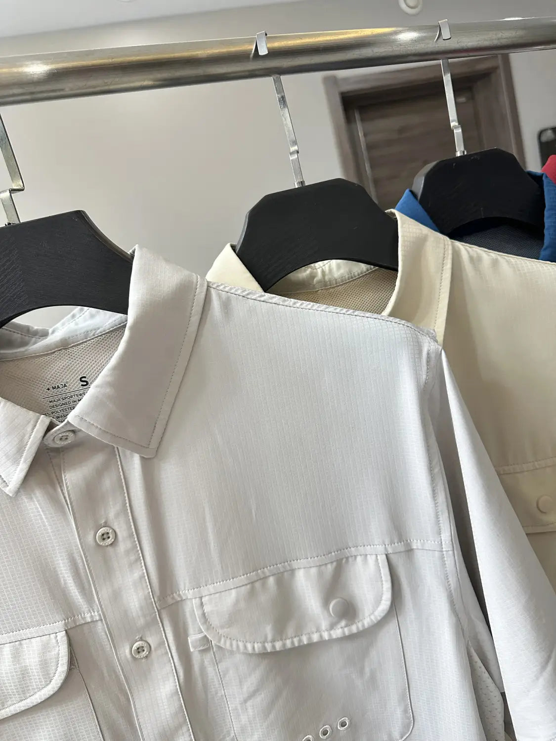 Ein markant weißes Herren-Stretch-Outdoorhemd mit strukturiertem Kragen, zwei Vordertaschen, subtilen Ziernähte-Details und schnelltrocknendem Stoff.