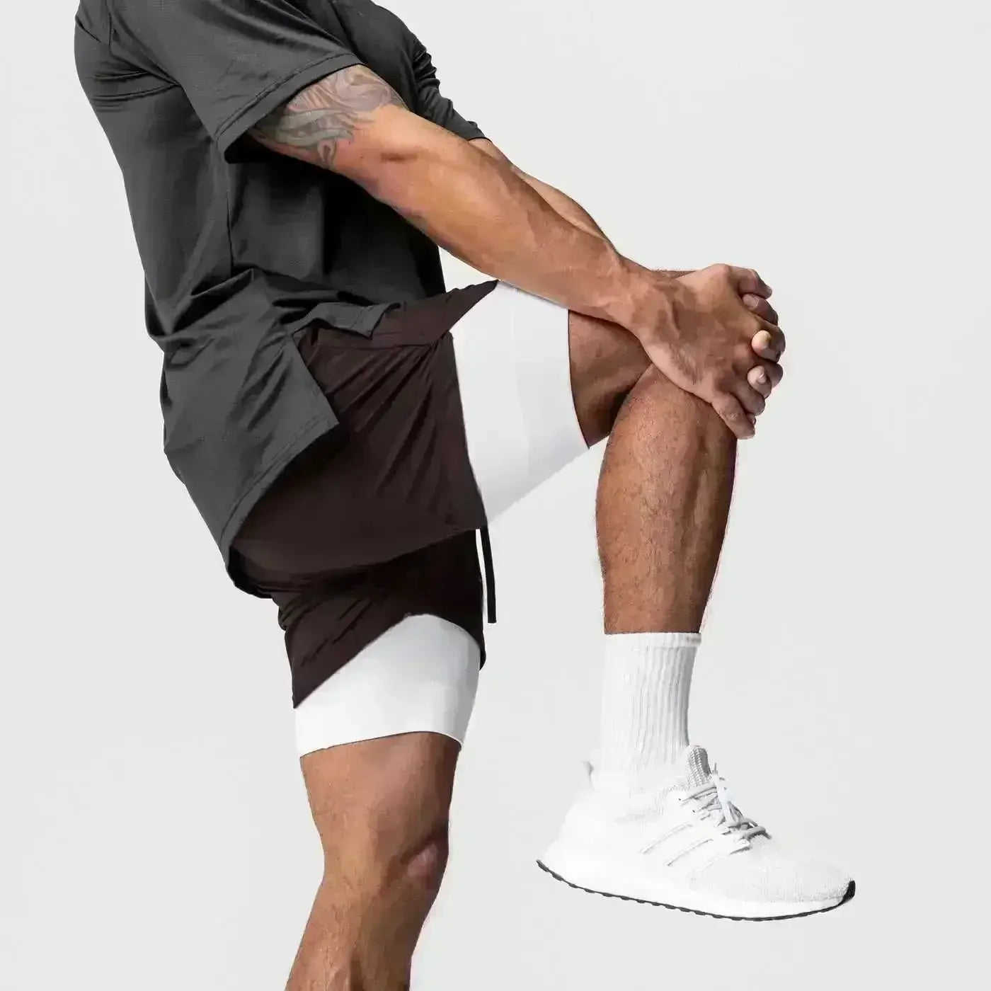 Zapatilla atlética blanca con suela negra y cordones grises, que acompaña a pantalones cortos de entrenamiento para anime 2 en 1 para gimnasio con trabilla para la toalla que ofrece soporte durante el ejercicio.