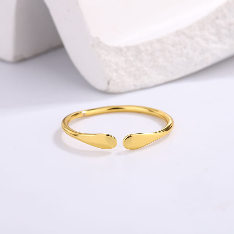 Un anillo apilable abierto de plata de ley con acabado en color dorado, con forma de gota, de diseño liso y elegante.