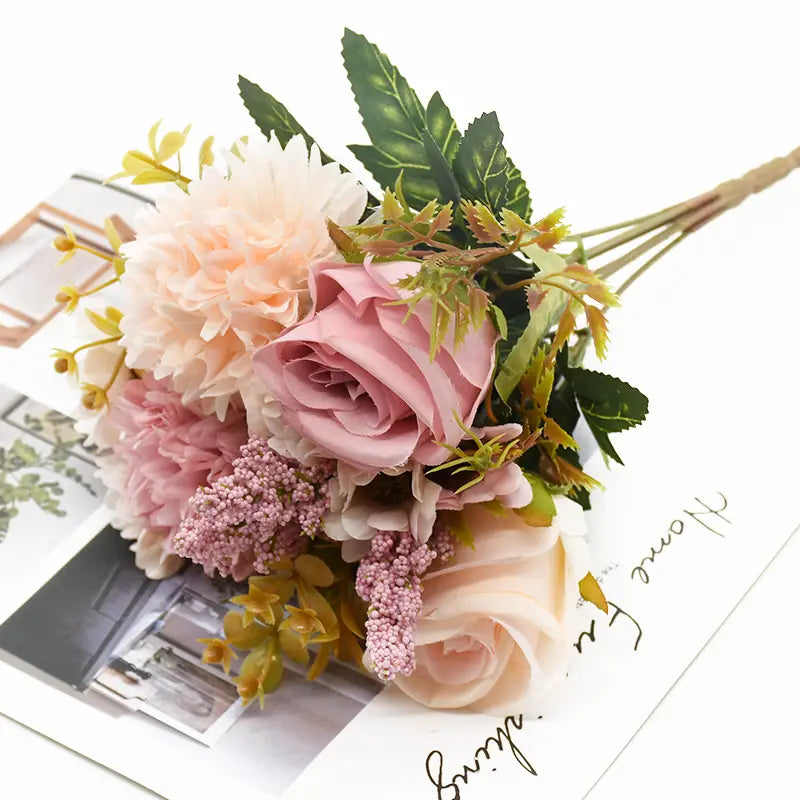 柔らかなピンクとピーチの、リアルなバラの花びらと緑の葉物をあしらった繊細な造花のバラのウェディングブーケ。