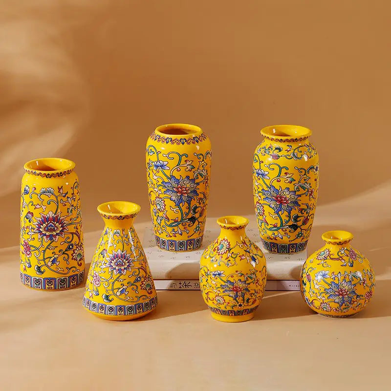 Ensemble de six petits vases en émail de céramique jaunes éclatants, avec des motifs floraux bleus et violets complexes, dans un style de porcelaine chinoise d’inspiration ancienne.