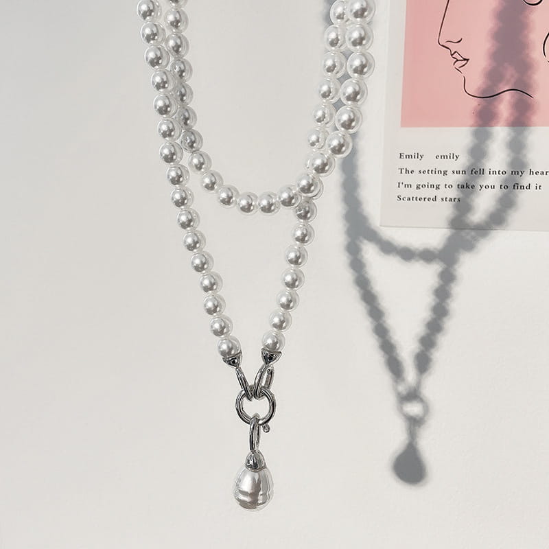 Un long collier délicat à double rang de perles en pendentif pour femmes, présentant un pendentif en forme de goutte.