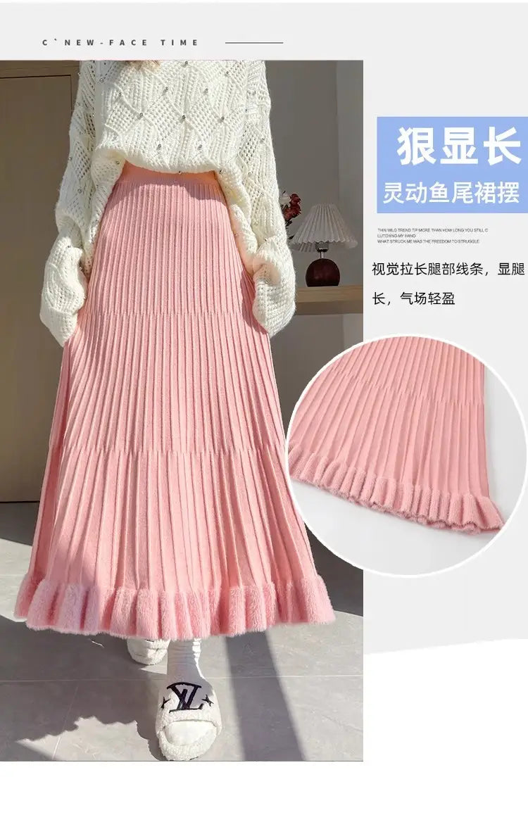 Une jupe mi-longue en maille rose tendre, avec plis à taille haute et ourlet volanté évasé.