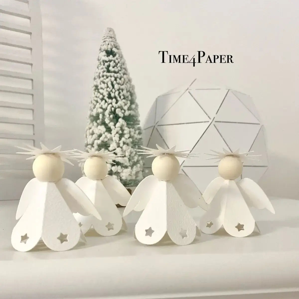 white paper angels with star-shaped cutouts on their wings and wooden spherical heads created using winter animal metal cutting dies for scrapbooking.