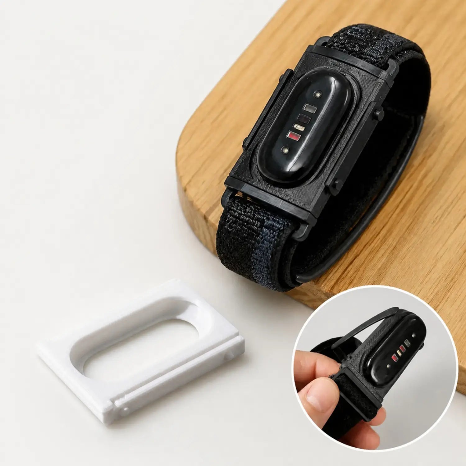 Black fitness tracker with a textured fabric strap and sleek rectangular digital display shown with an adapter bracket frame for Fitbit Air to Whoop 5.0.