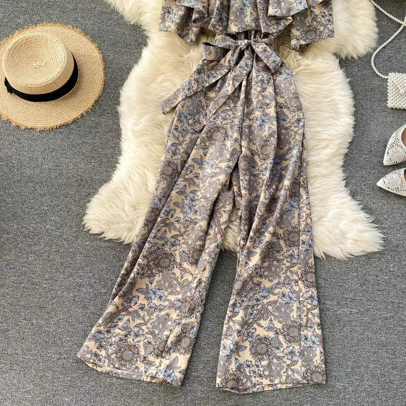 Pantalón de pierna ancha con estampado floral beige y gris con cintura atada, presentado como un enterizo floral de pierna ancha con escote tipo bardot.