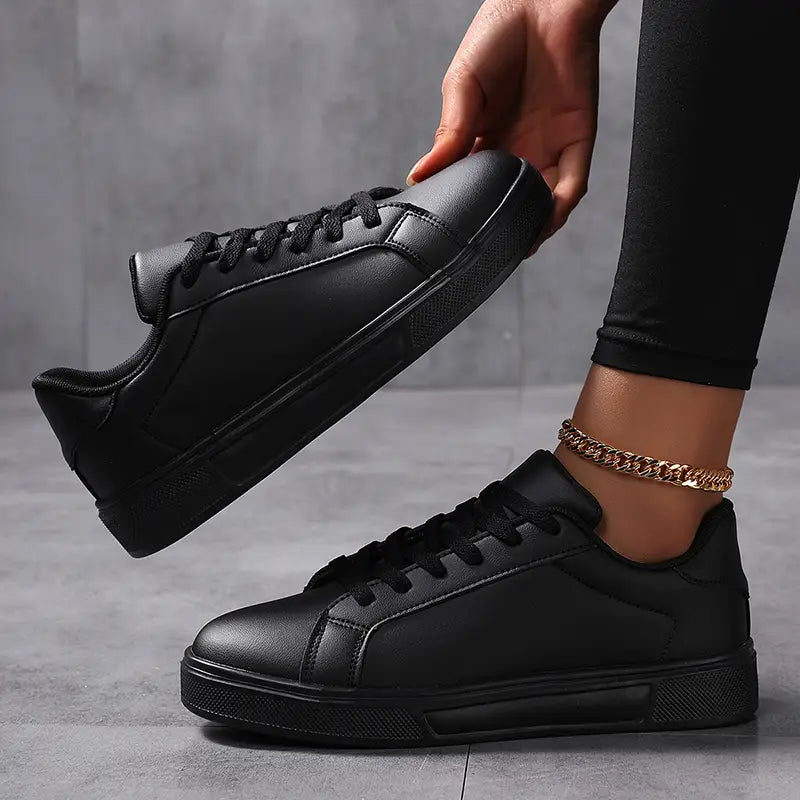 Schwarze Ledersneaker im Low-Top-Format mit schwarzen Schnürsenkeln und einer strukturierten Gummisohle, als leichte Freizeitsportschuhe ausgelegt.