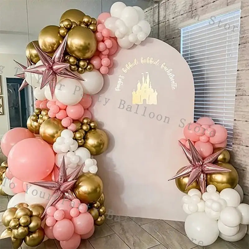 A decorative pink balloon arch kit featuring clusters of pink, gold, and white balloons with metallic rose gold star-shaped accents for wedding and birthday parties.