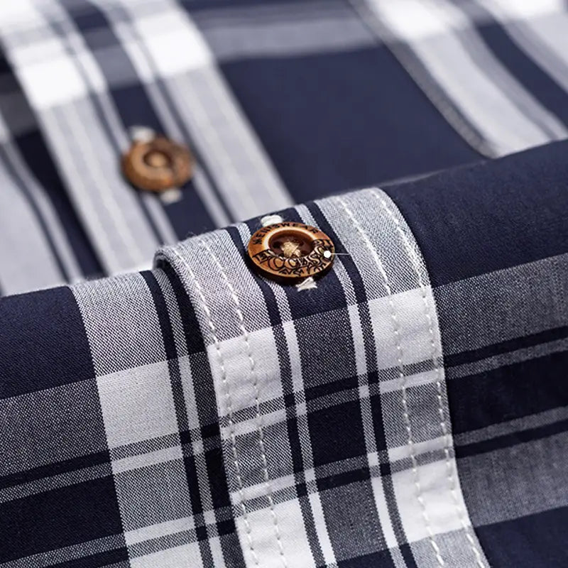 A wooden button with engraved text is featured on the cuff of a men’s cotton navy and white plaid long sleeve slim fit shirt.